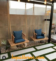 two wooden chairs sitting on top of a grass covered patio