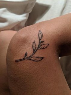 a woman's arm with a tattoo on it that has a branch and leaves on it