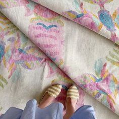 a pair of shoes sitting on top of a flowered blanket next to a person's feet