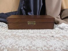 a wooden box sitting on top of a white lace covered tablecloth next to a curtain