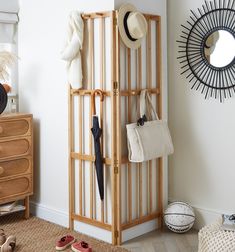 a wooden rack with umbrellas and hats on it in a white room next to a dresser