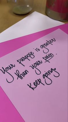 a piece of pink paper with writing on it sitting on top of a wooden table