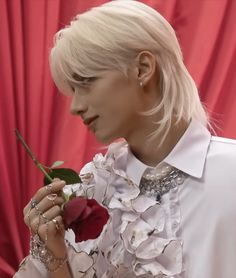 a woman with blonde hair holding a rose