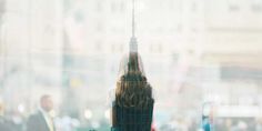 there is a large clock tower seen through the glass window in this cityscape