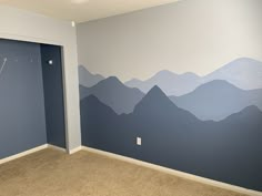 an empty room with mountains painted on the wall and a clock mounted to the wall