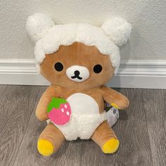 a brown teddy bear sitting on top of a wooden floor next to a white wall