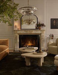 a living room filled with furniture and a fire place under a chandelier hanging from the ceiling