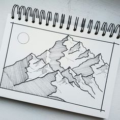 a drawing of mountains on a piece of paper next to a pen and ink marker