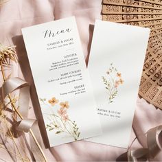 two wedding program cards with flowers on them next to some lace and ribbon bows, along with other items