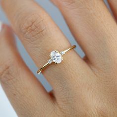 a woman's hand with a diamond ring on top of her finger, showing the center stone