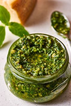 a jar filled with pesto next to bread