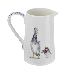 a white pitcher with an image of two chickens on it's side and one bird standing next to the pitcher