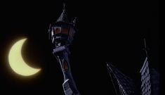 the moon is seen behind a tower with a clock on it's side in front of some buildings