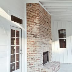 a brick fireplace in the corner of a room with white walls and doors on either side