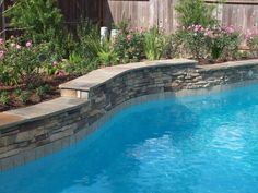 a swimming pool surrounded by landscaping and flowers