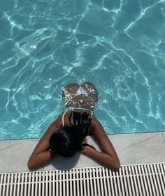 a woman laying on the ground in front of a swimming pool with clear blue water