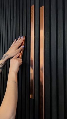 a woman's hand is touching the door handle on a black and gold wall