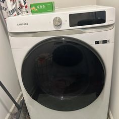 a washing machine with the door open in a small room next to a wall and floor