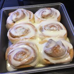 a pan filled with cinnamon rolls covered in icing