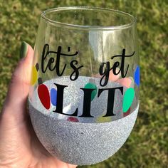 a hand holding up a wine glass that says let's get lit