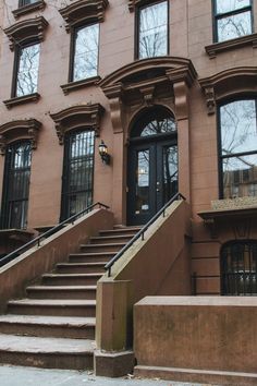 an apartment building with stairs leading up to the front door and windows on each side