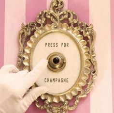 a person in white gloves points at a plaque that says press for champagne on it