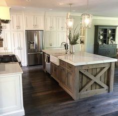 a large kitchen with an island in the middle of it and two lights hanging from the ceiling