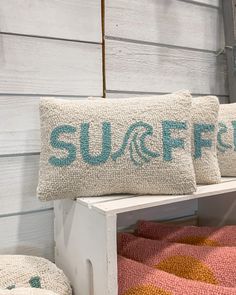 two pillows sitting on top of a white bench next to a wooden wall with the word suff fish painted on it