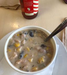 a white bowl filled with soup next to a bottle of ketchup on a table