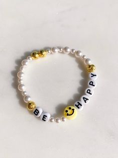 A smiley face and pearls...can't go wrong! Stack it with others or wear it alone and this bracelet will make you smile every time you look at it. stretchy one size made locally! All accessories are final sale. Friendship Bracelets Smiley Face, Be Happy Bracelet, Bracelet With Words Ideas, Smile Face Bracelet, Beaded Bracelets Cute, Smiley Face Bracelet Ideas, Holiday Beaded Bracelets, Bracelet Ideas Words, Stretchy Bracelets Diy