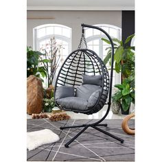 an indoor swing chair with grey cushions and black frame, in the middle of a living room