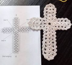 a crocheted cross sitting on top of a piece of paper