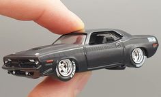 a toy car is being held in the palm of a person's hand,