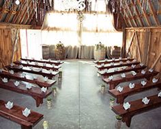 an empty barn with tables and benches in the center, set up for a formal function