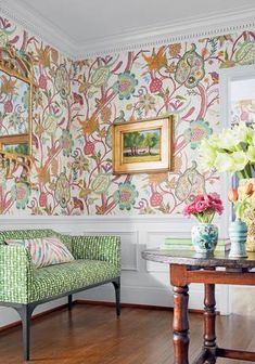 a living room with floral wallpaper and green chairs in front of a table filled with flowers