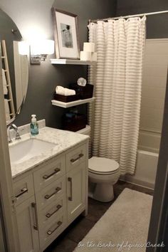 a bathroom with a toilet, sink and shower curtain in it's corner area