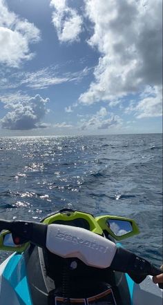 a person riding on the back of a boat in the ocean under a cloudy sky