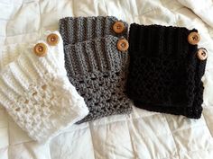 three crocheted mittens are laying on a white bed with buttoned buttons