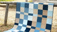 a blue and tan quilt hanging on a wooden fence post in front of a house