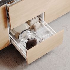 an open drawer with dishes in it on the floor next to a sink and counter top