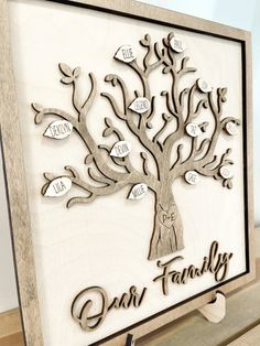 a family tree cutout with the names and date on it, hanging from a wooden frame