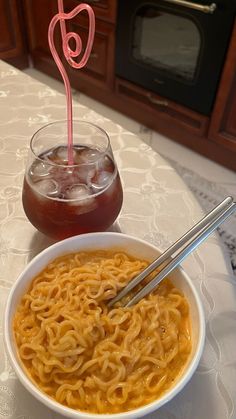 there is a bowl of noodles and a drink on the table