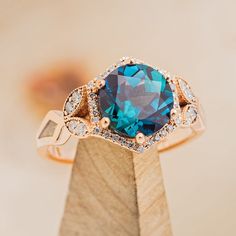 a ring with a blue topaz surrounded by white and brown diamonds on a wooden stand