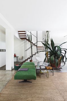 a living room filled with furniture next to a stair case and potted plant on top of a table