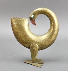 a gold colored bird shaped object sitting on top of a metal stand with a turquoise stone in it's beak