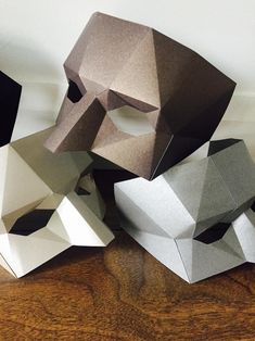 three paper masks sitting on top of a wooden table