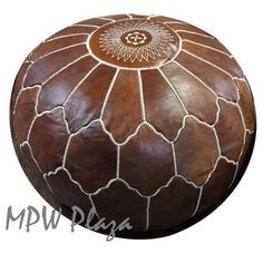 a brown leather poufce with white stitching on the top and bottom, is shown