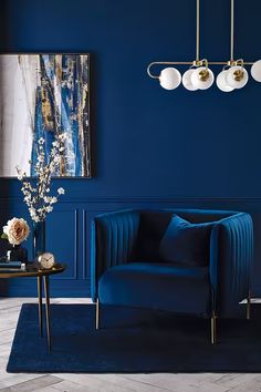 a living room with dark blue walls and gold accents on the furniture, along with white flowers