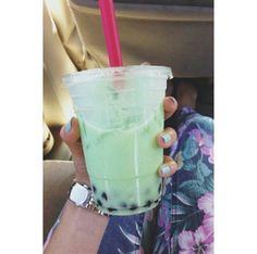 a woman holding a drink in her hand while sitting in the back seat of a car