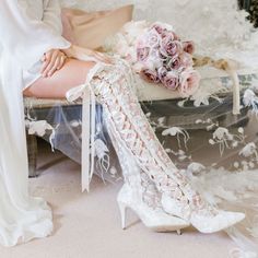 a woman sitting on top of a couch next to a bouquet of flowers and high heels